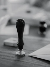 A wooden stamp sits on a wooden desk