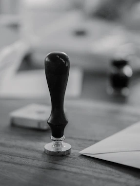 A wooden stamp sits on a wooden desk.