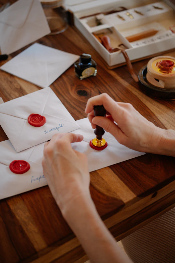 Hands sealing envelopes with red wax seals.