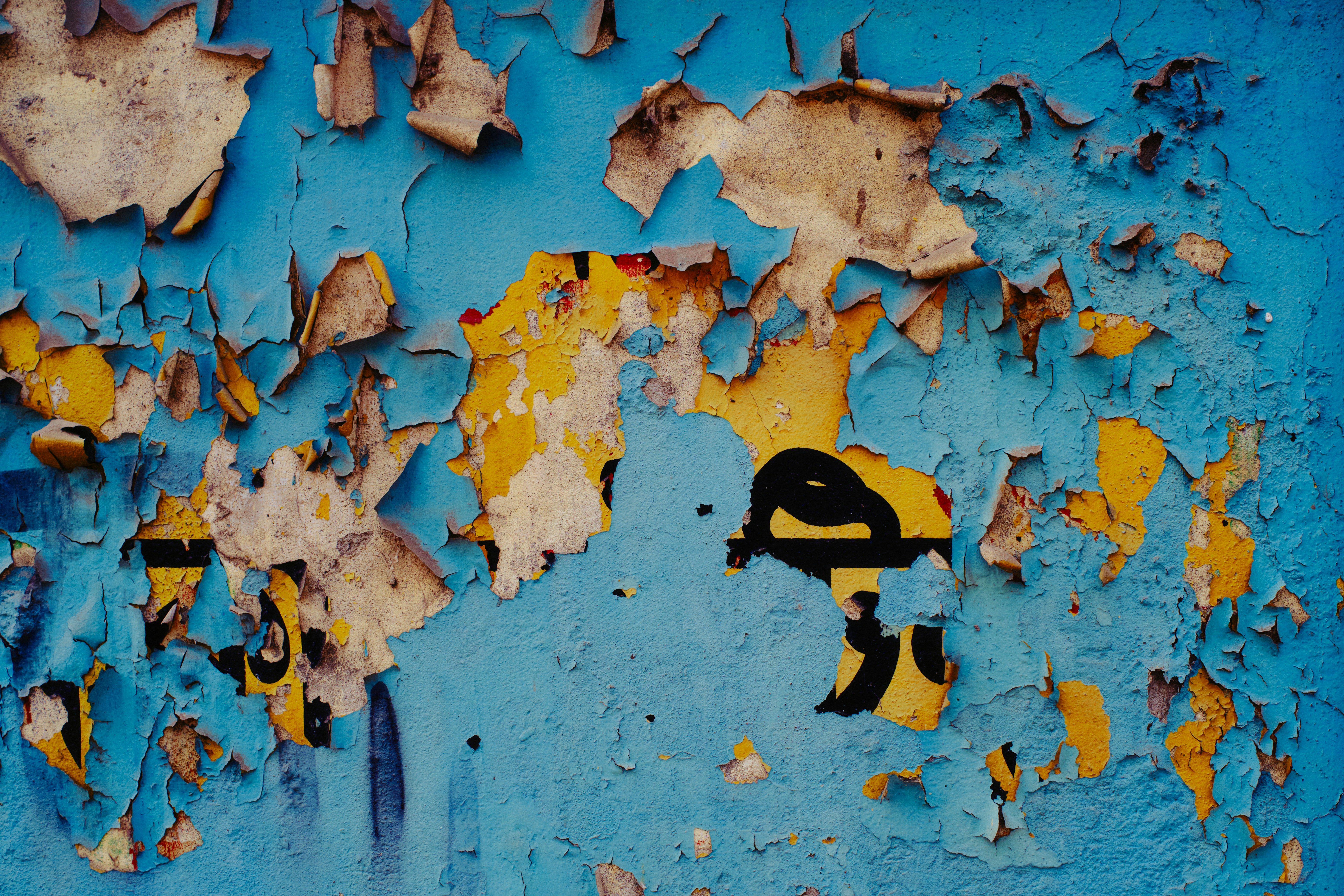 Peeling blue paint reveals yellow underneath