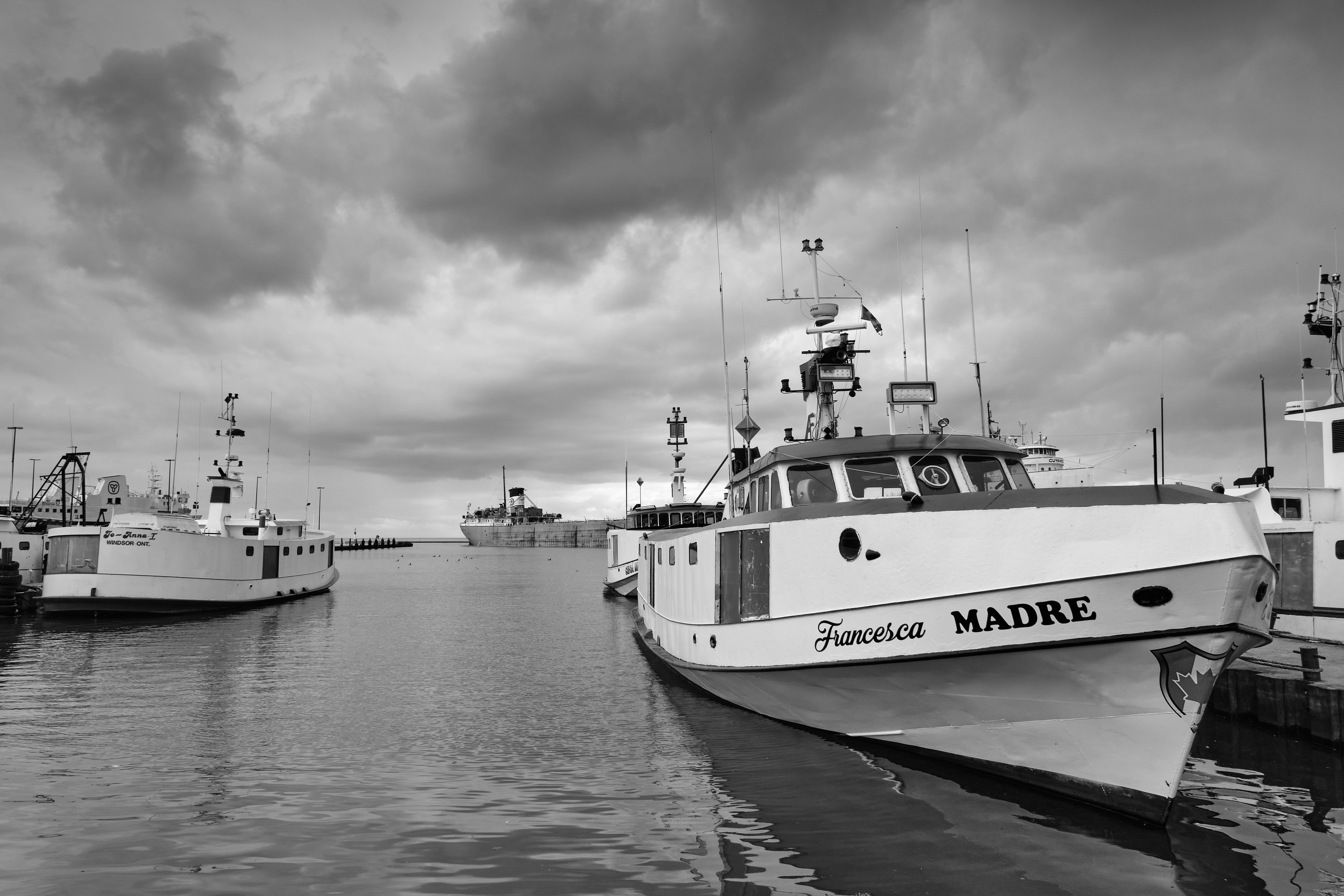 Fishing boats docked in a calm harbor under cloudy skies