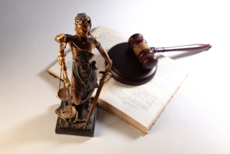 Statue of justice, gavel, and open book on table.