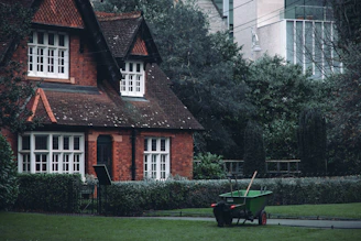 A red brick house with a green garden cart outside