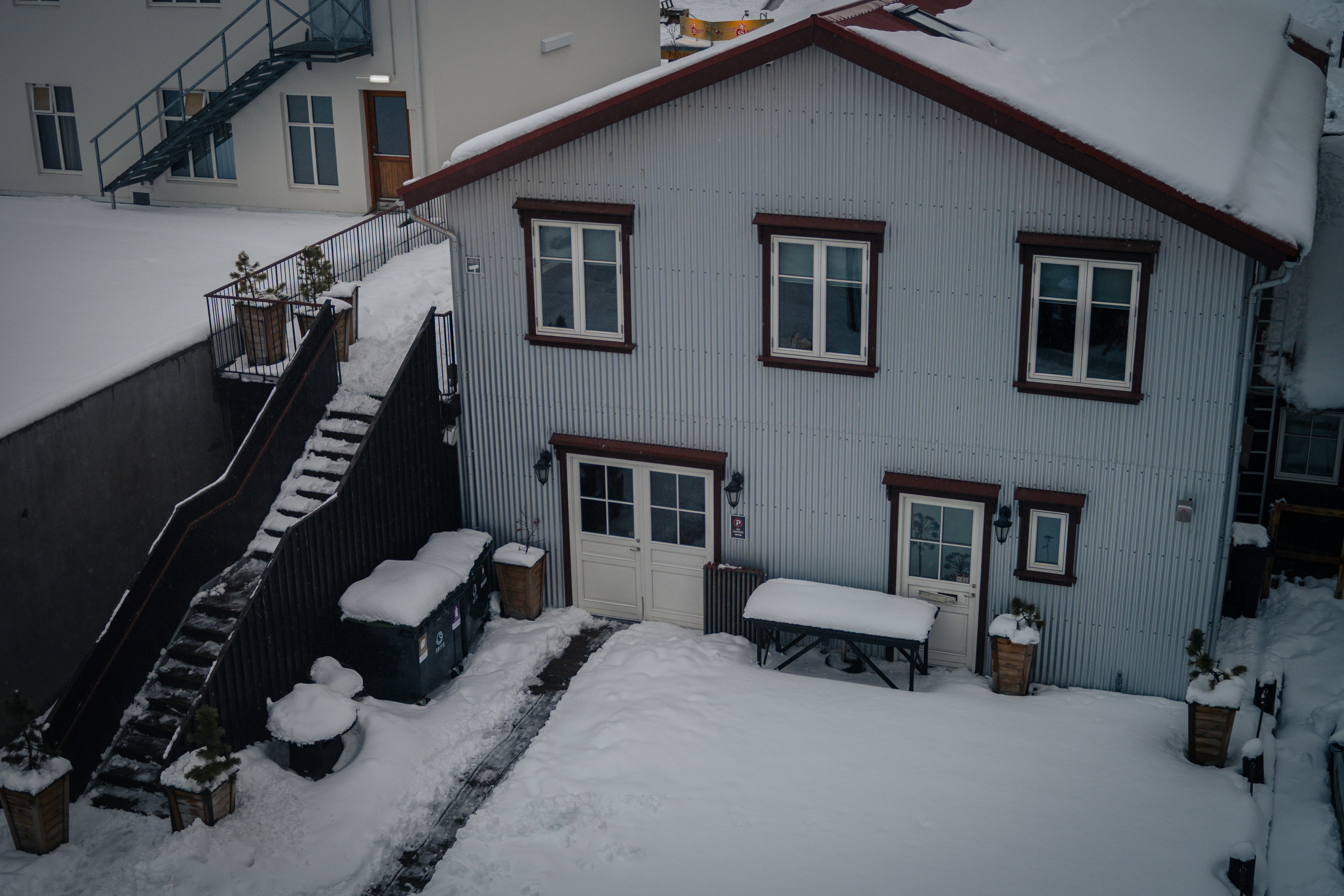 Uma casa com quintal coberto de neve e assentos ao ar livre.