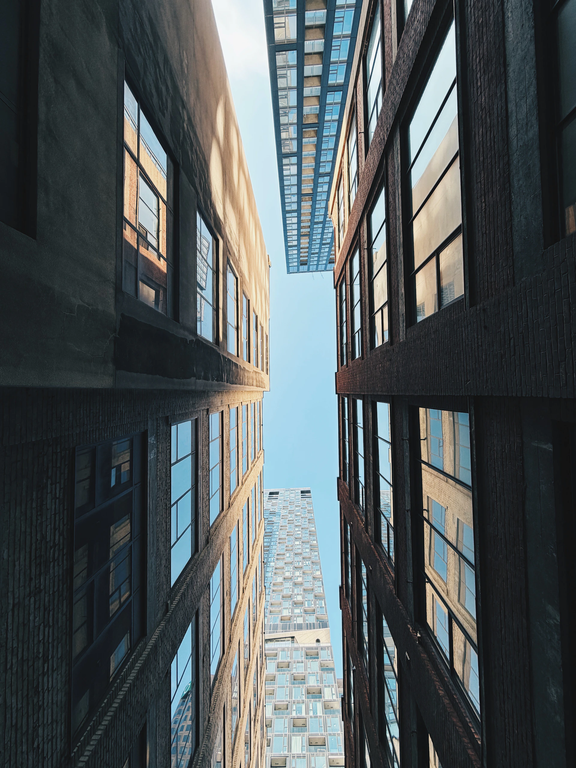 Looking up between tall buildings towards the sky