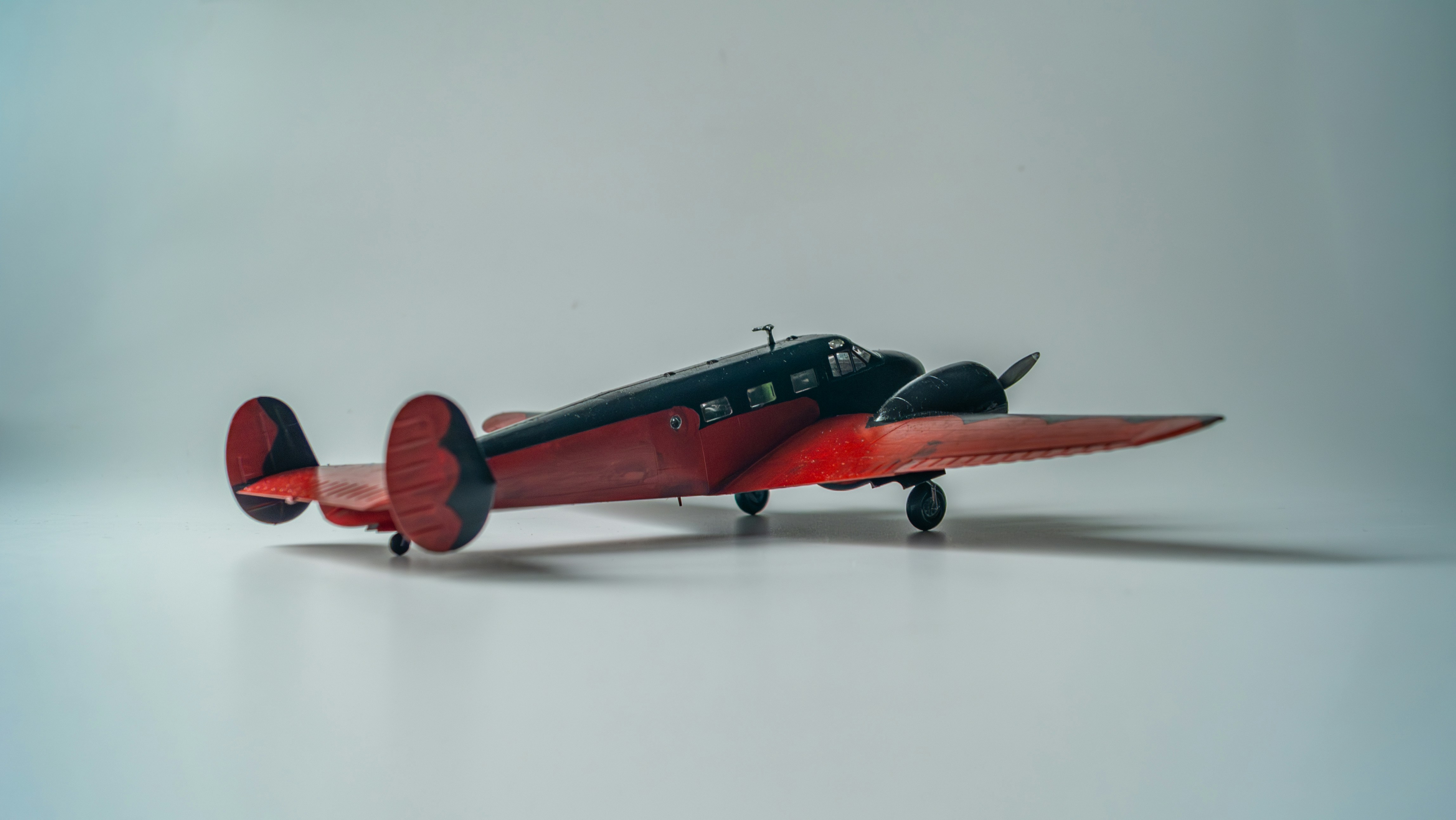 A vintage red and black airplane on a white background