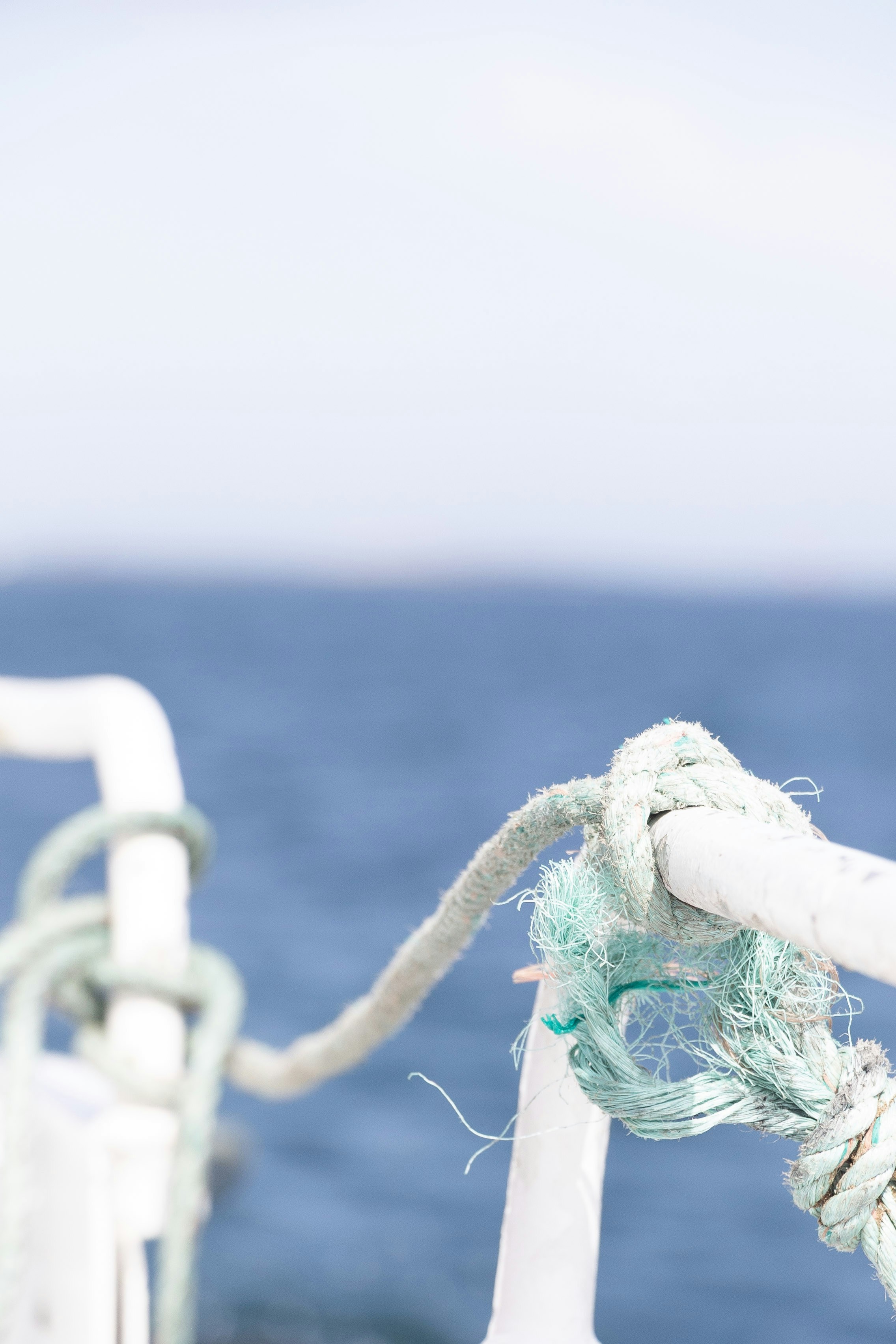 Seil, das an ein Geländer mit ozeanartigem Hintergrund befestigt ist