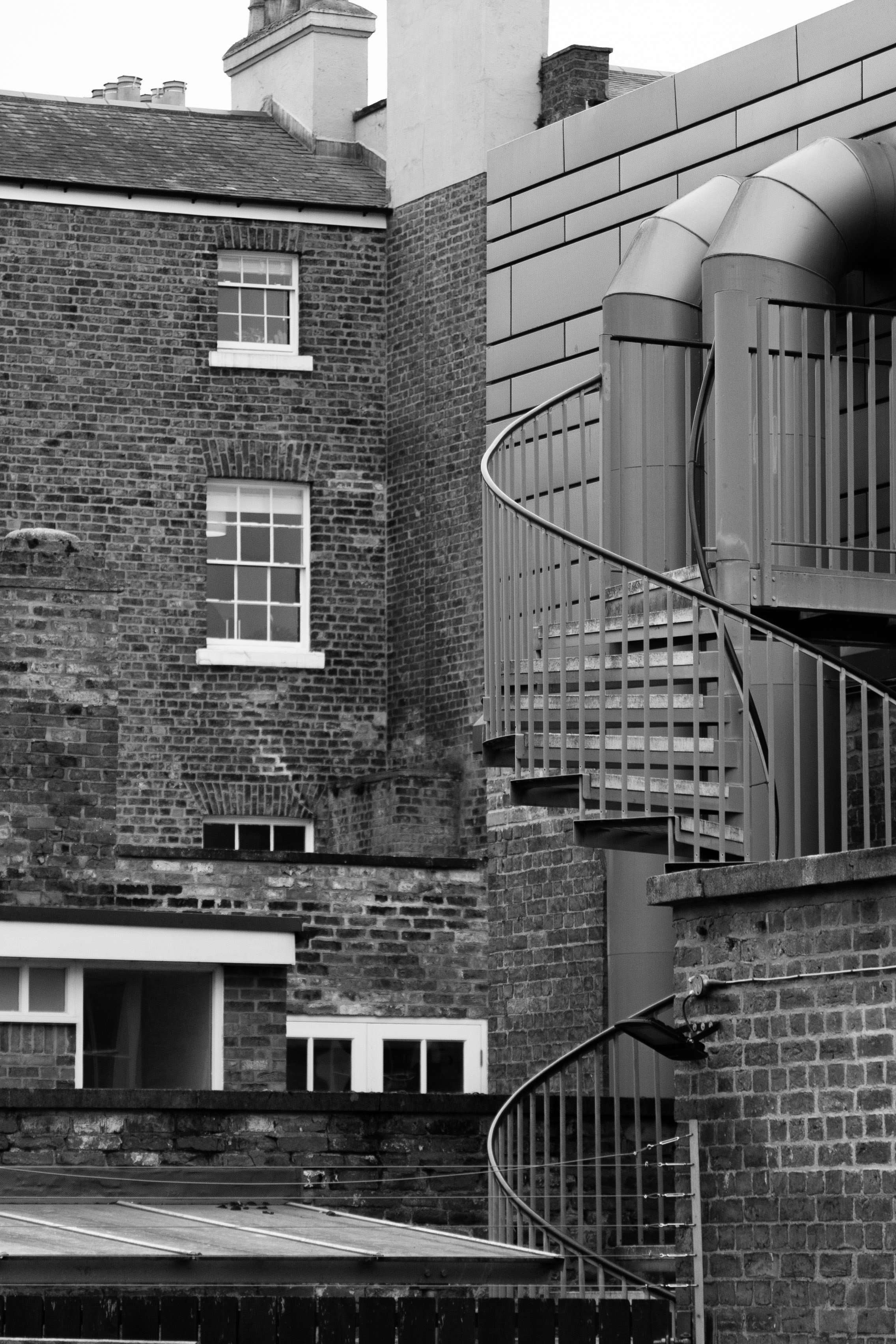 Wendeltreppe gegen Backsteingebäude und moderne Bauabschnitte