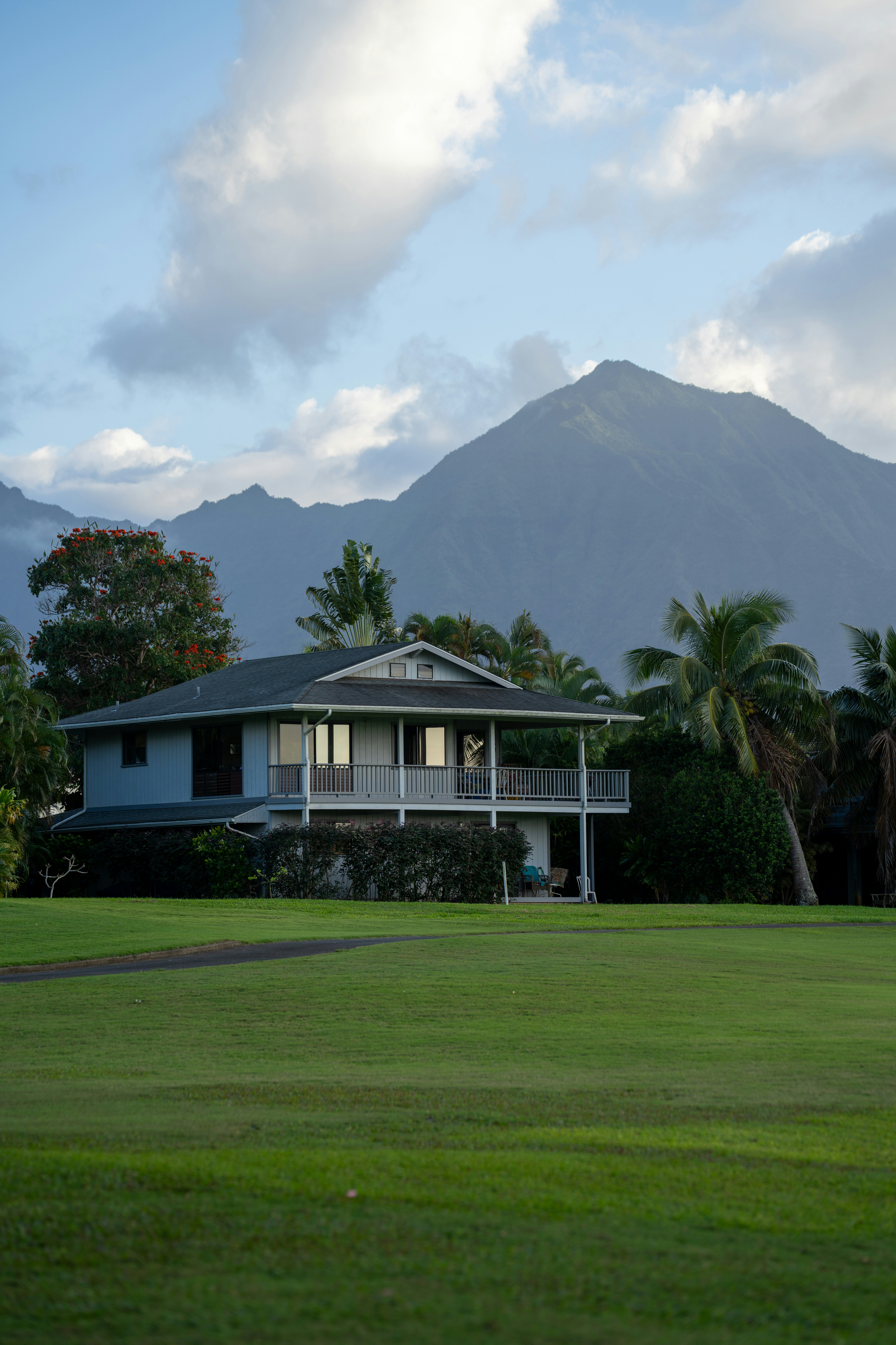 Una casa moderna su un prato verde con montagne dietro.