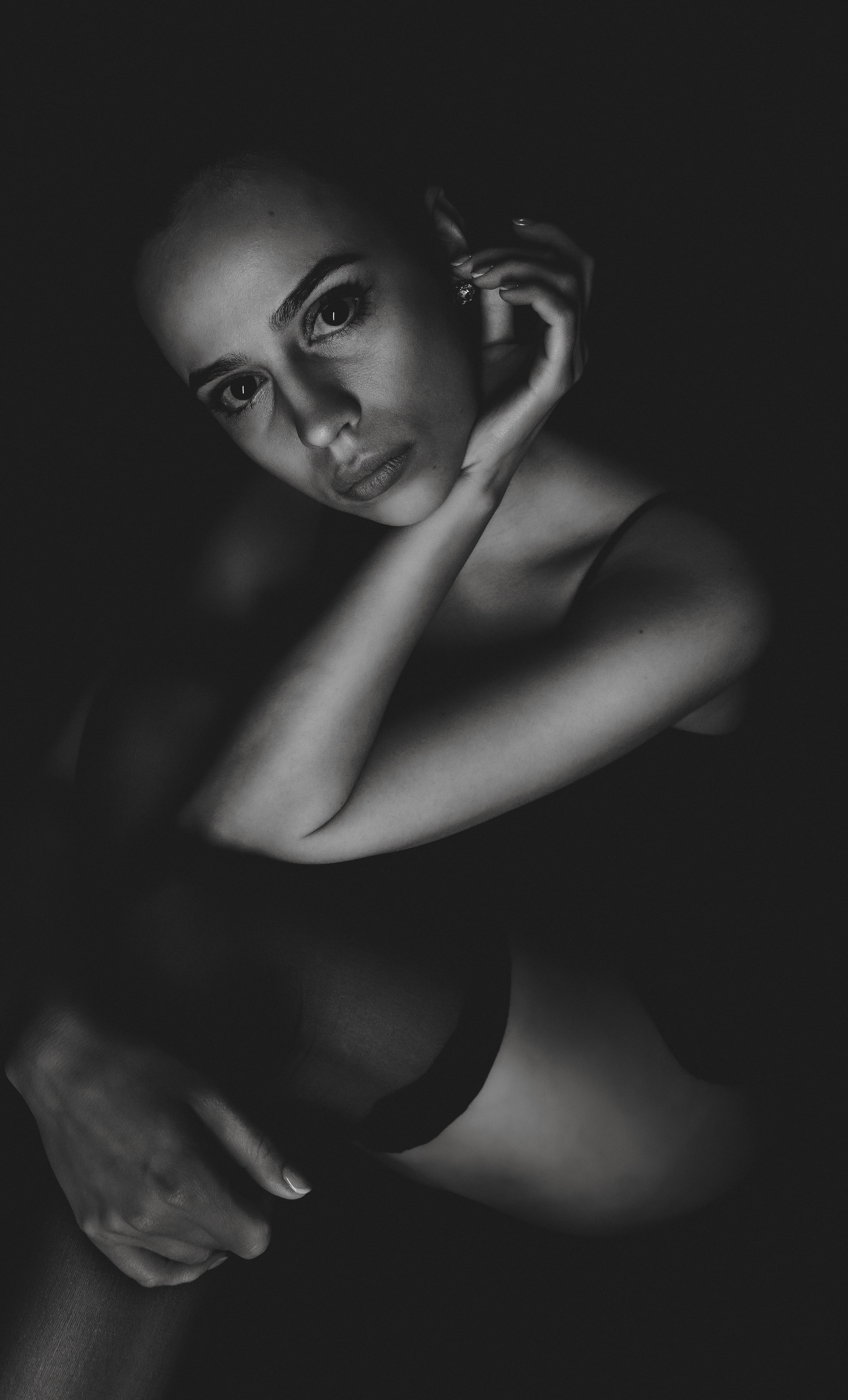 Eine Frau mit der Hand am Kinn im Dunkeln.