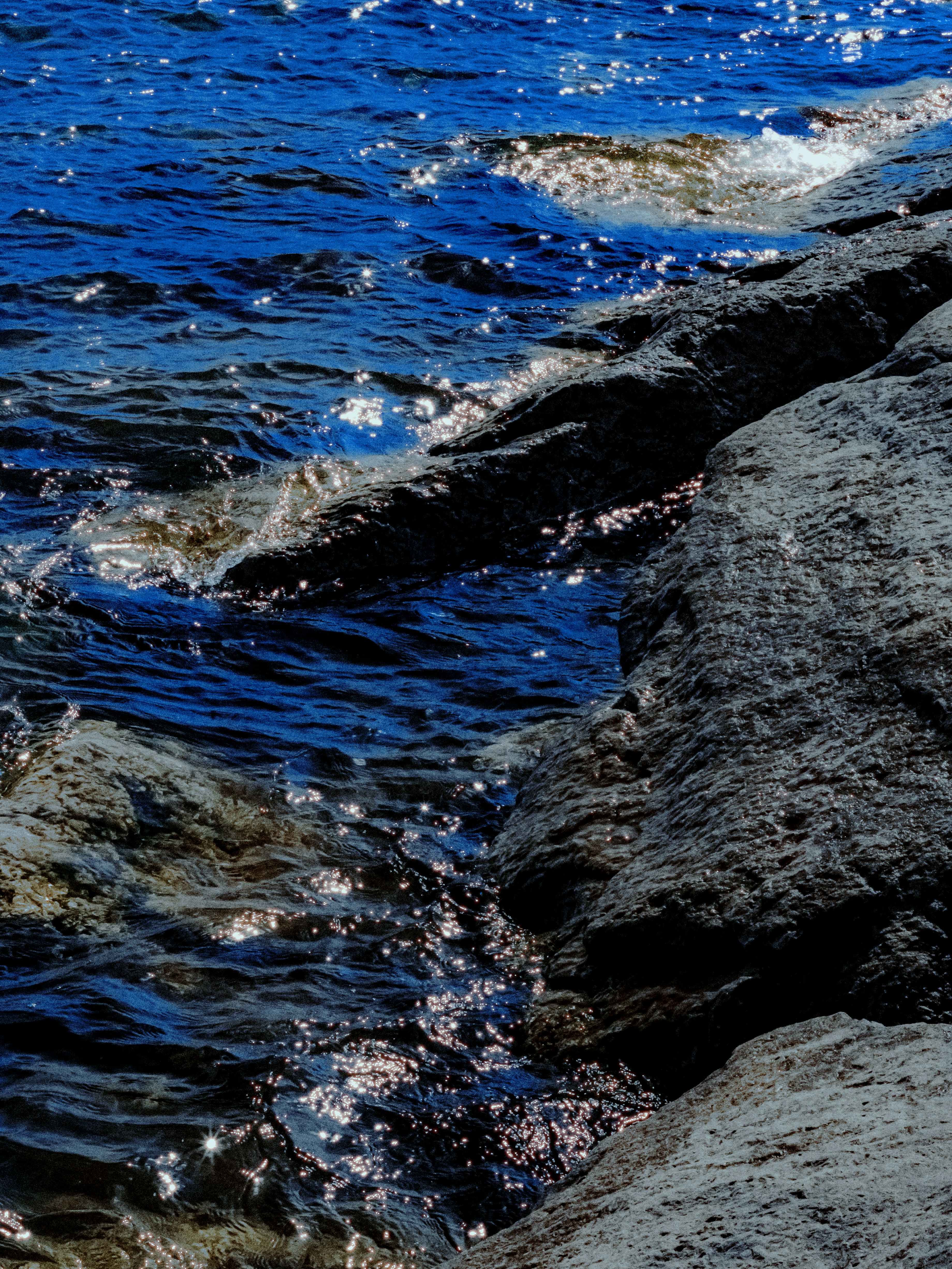 Dark rocks meet sparkling blue ocean waves