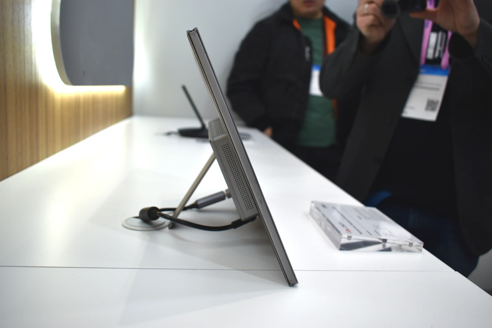 Slim portable monitor on a kickstand with a USB-C cable plugged into the side on a white table