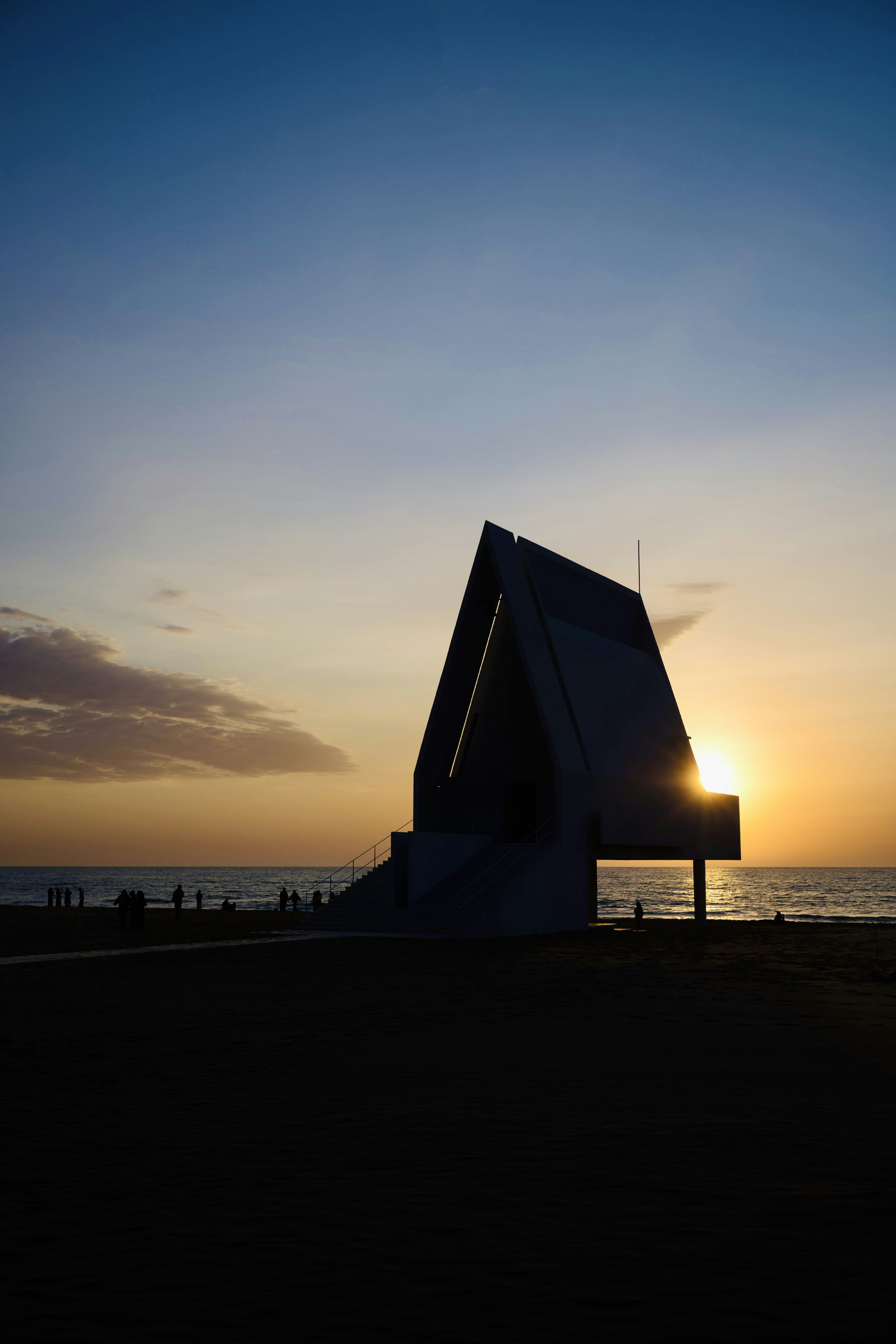 Modern building silhouette against a sunset beach