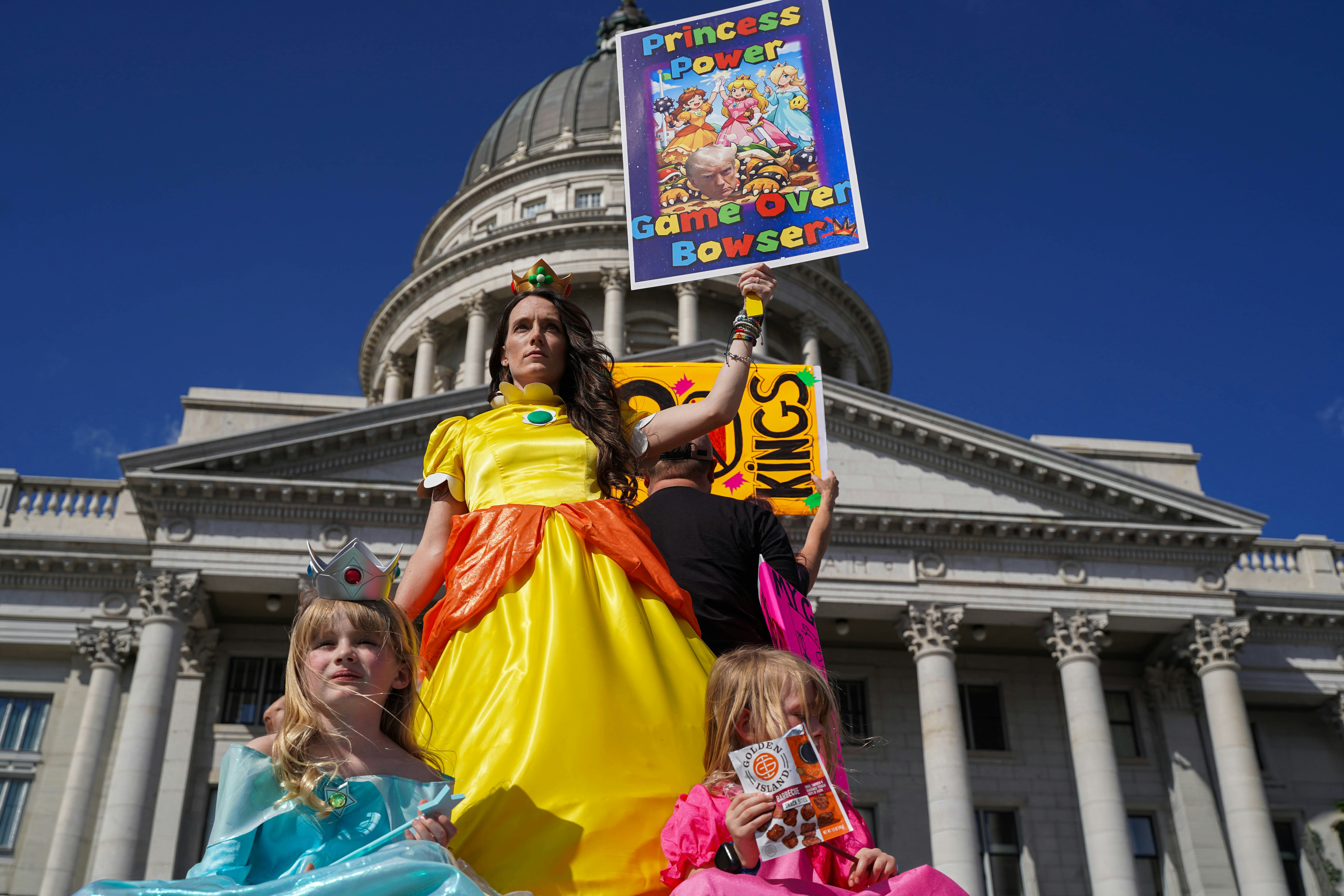 Woman in princess costume holds protest sign