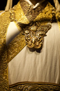 Ornate golden mask adorns white ceremonial garment.