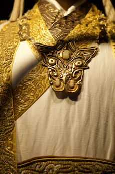 Ornate golden mask adorns white ceremonial garment.