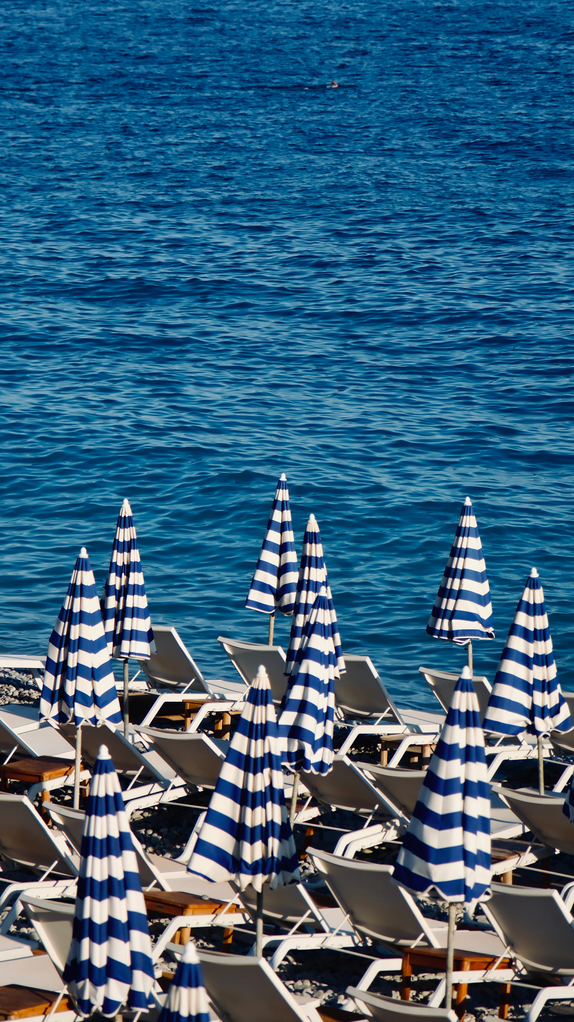 Beach chairs and outdoor leisure equipment arranged beside blue coastal water