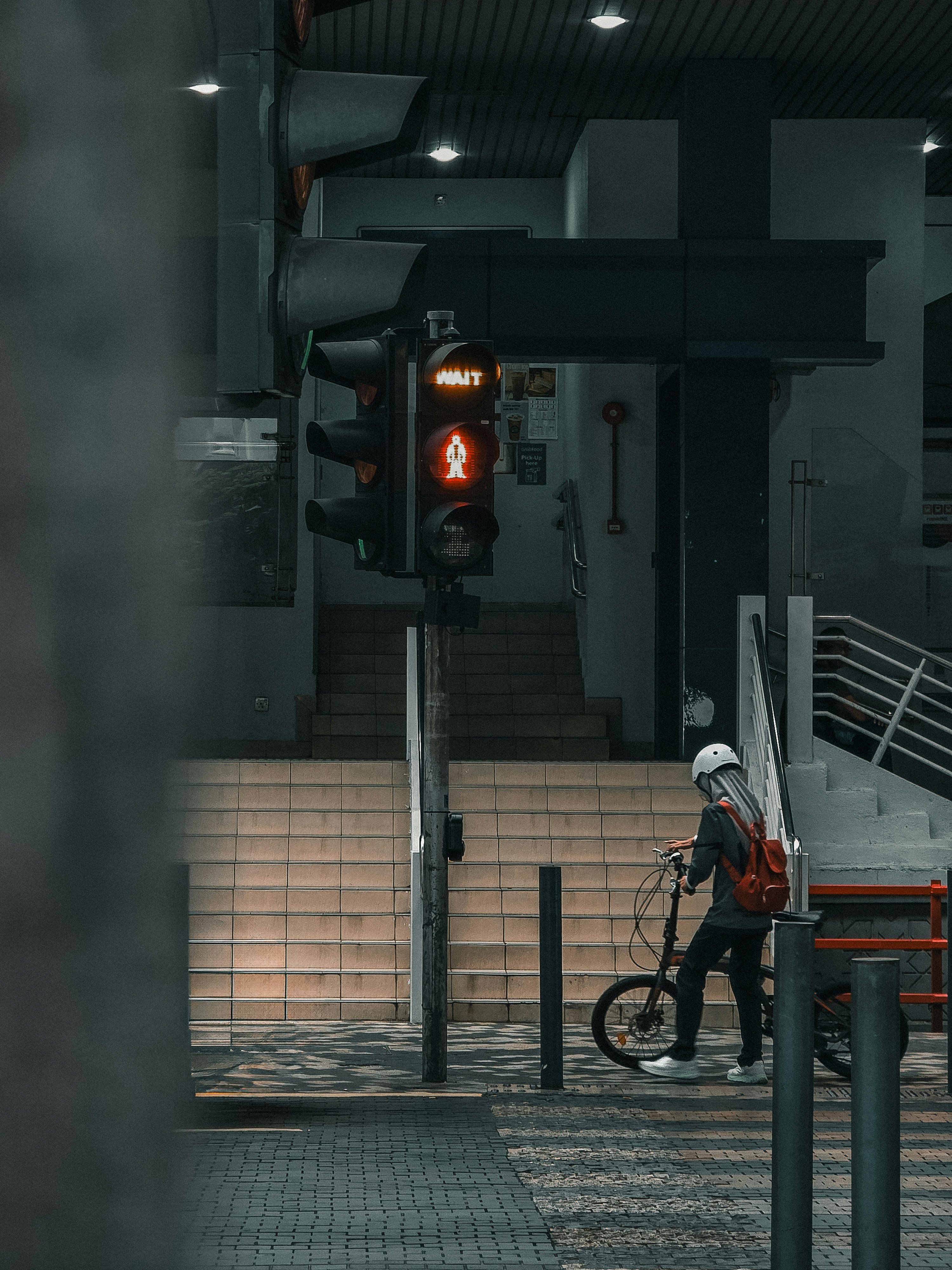 Cyclist waiting with a bicycle at an urban traffic light