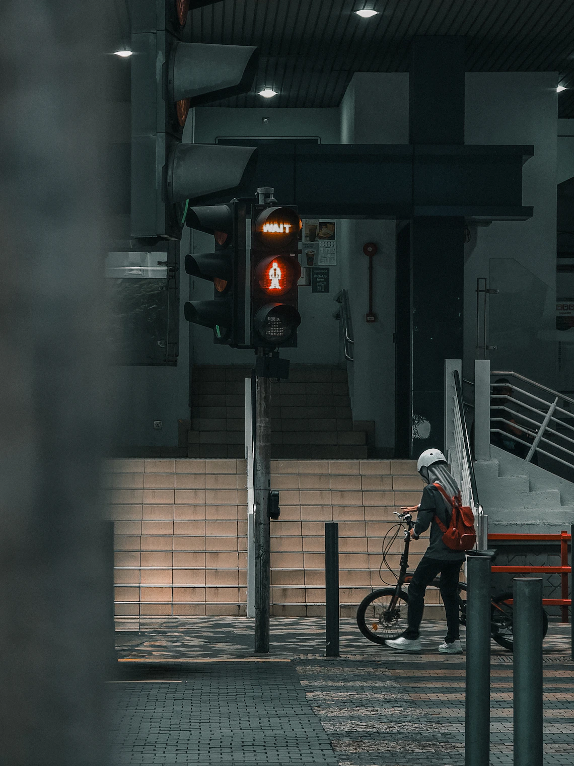 Cyclist waiting with a bicycle at a city traffic signal