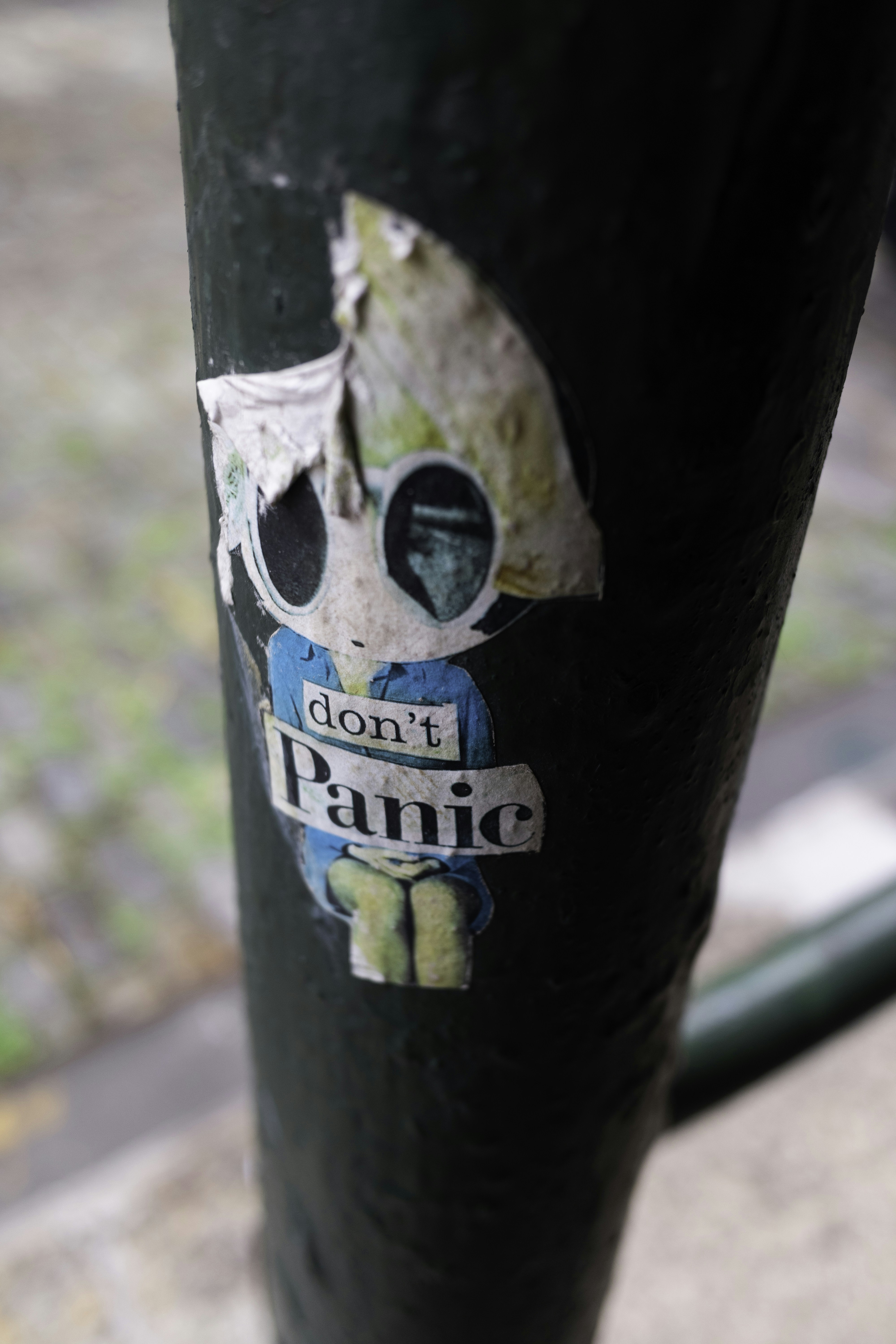 A sticker with "don't panic" on a pole