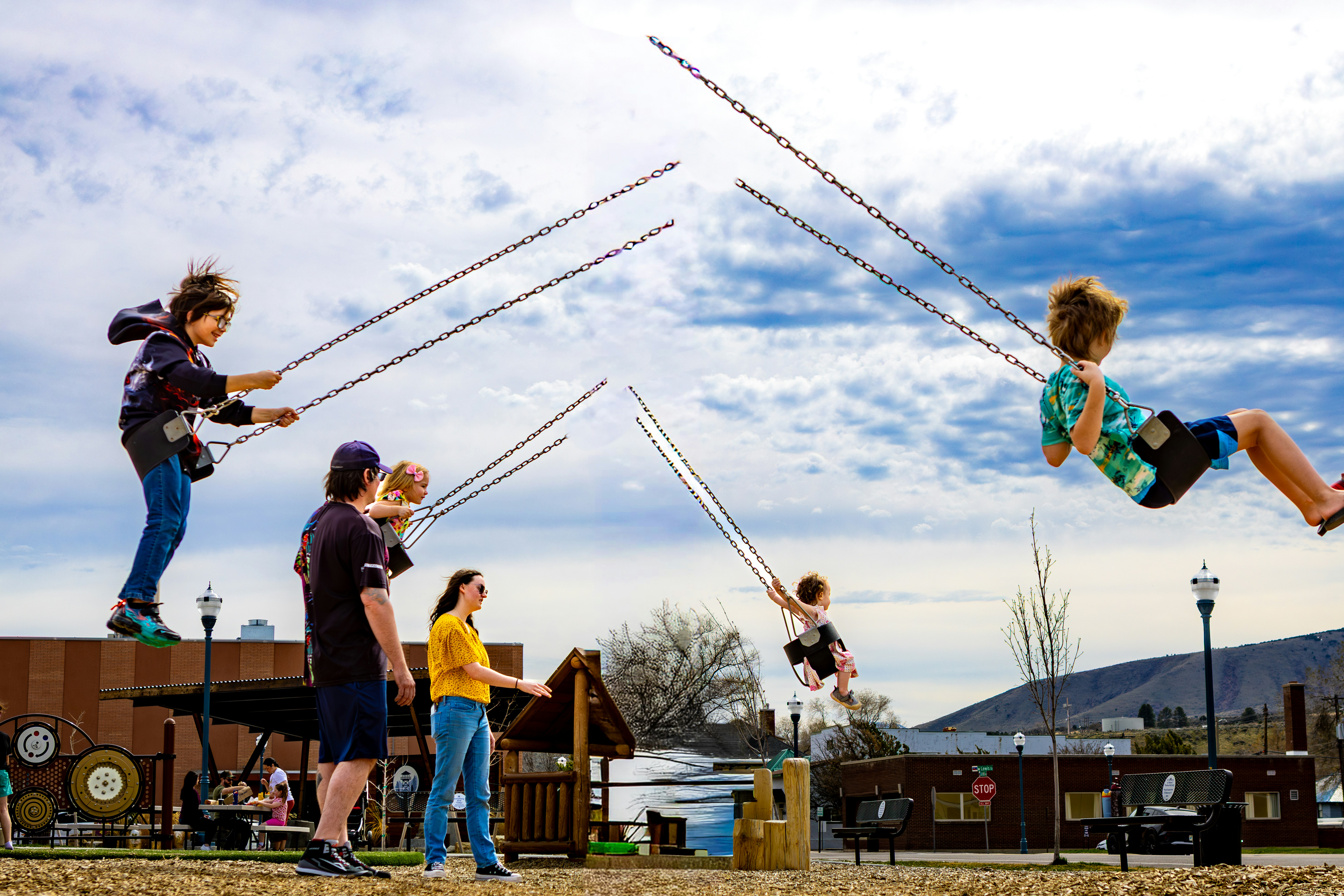 Children swinging high on ropes against a cloudy sky
