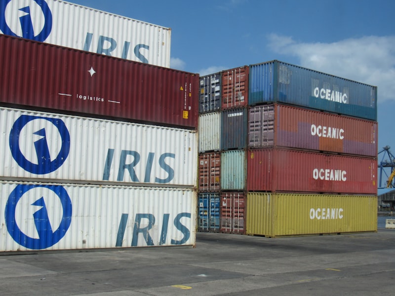 Stacked shipping containers at a port under a blue sky