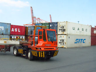 Orange terminal tractor with shipping containers at port