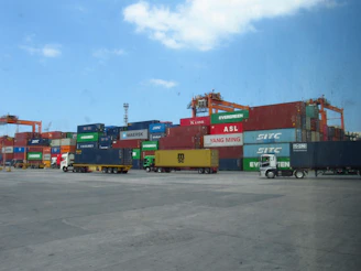 Shipping containers stacked at a busy port with trucks