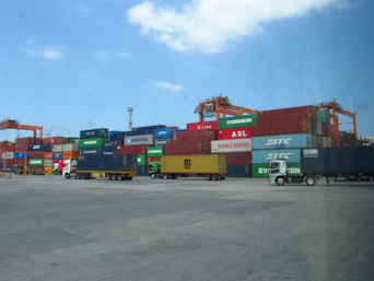 Shipping containers stacked at a busy port with trucks.