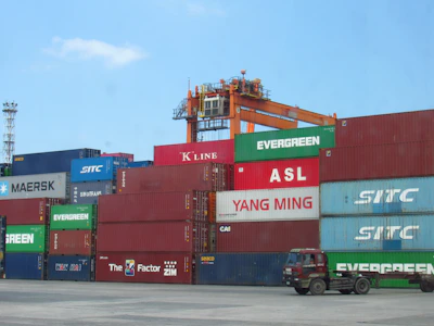 Stacked shipping containers at a port with a crane.