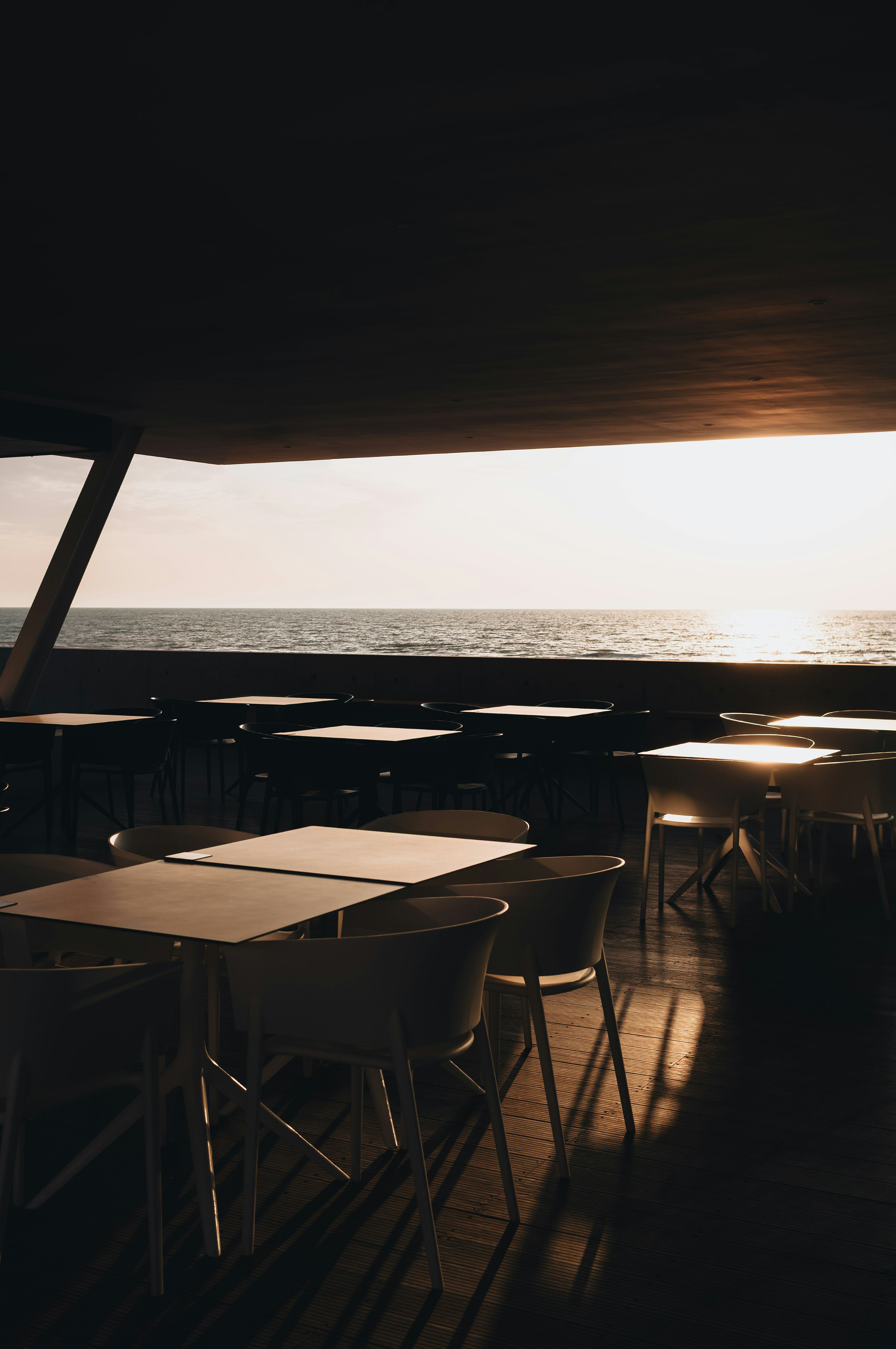 Empty cafe tables by the ocean at sunset.
