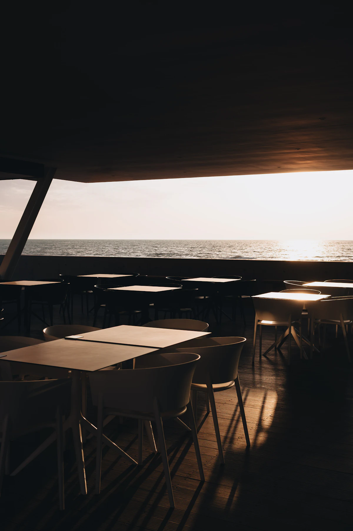 Tables above the water at dusk. Illustrative editorial image, not a photograph of Fjord Badehus.