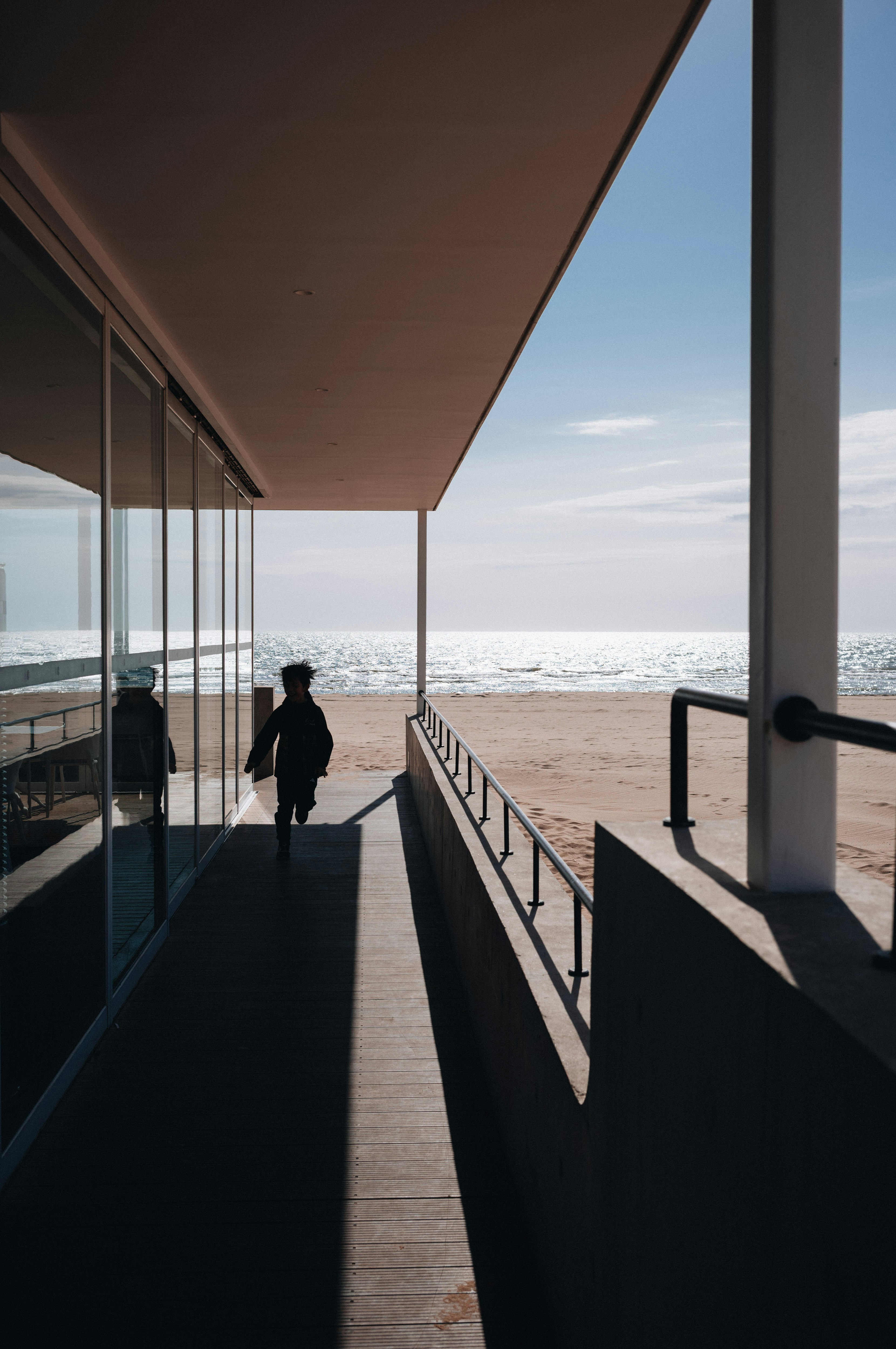 Child walks towards the ocean under a modern overhang