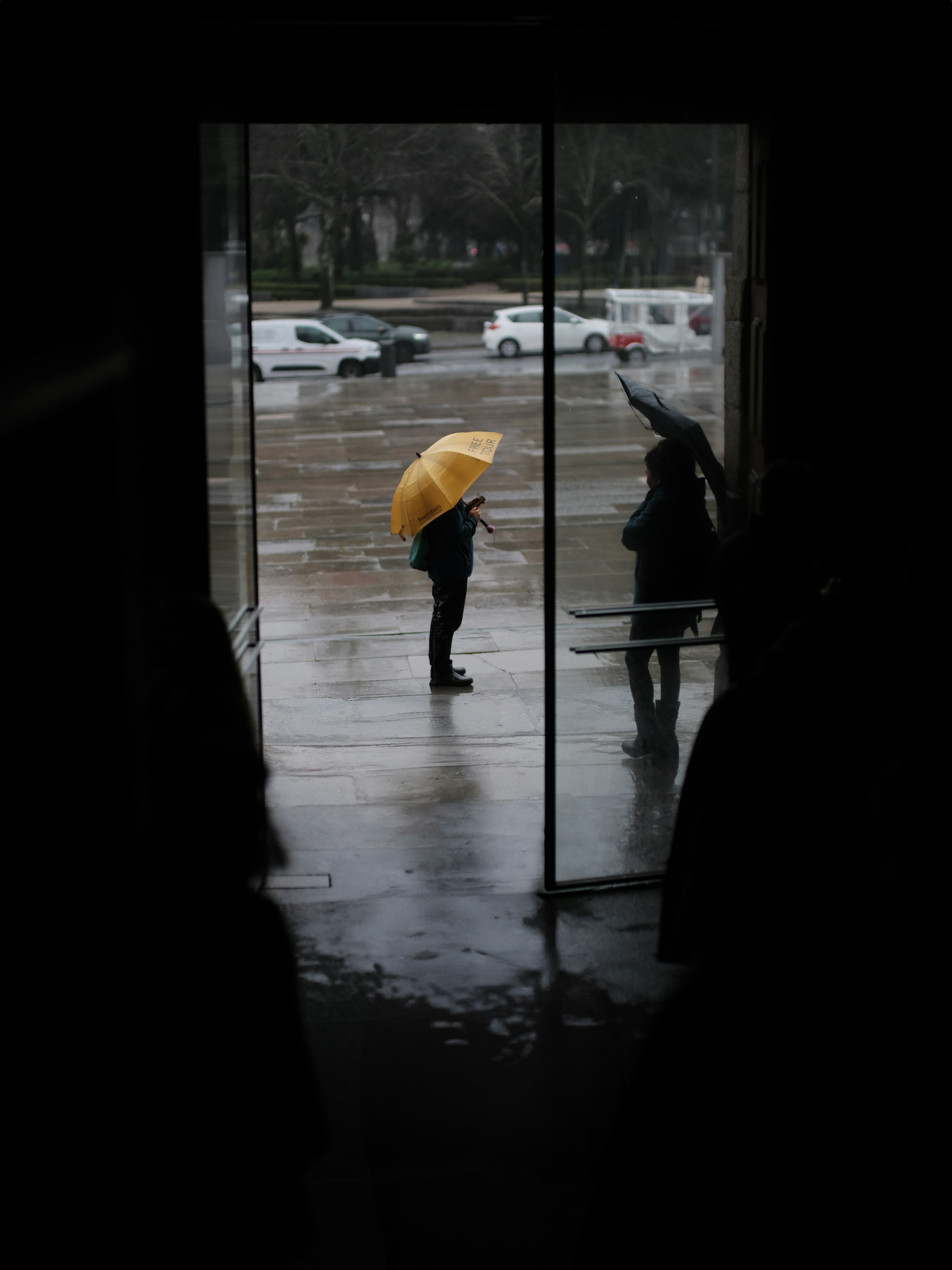 Person with yellow umbrella standing in rain