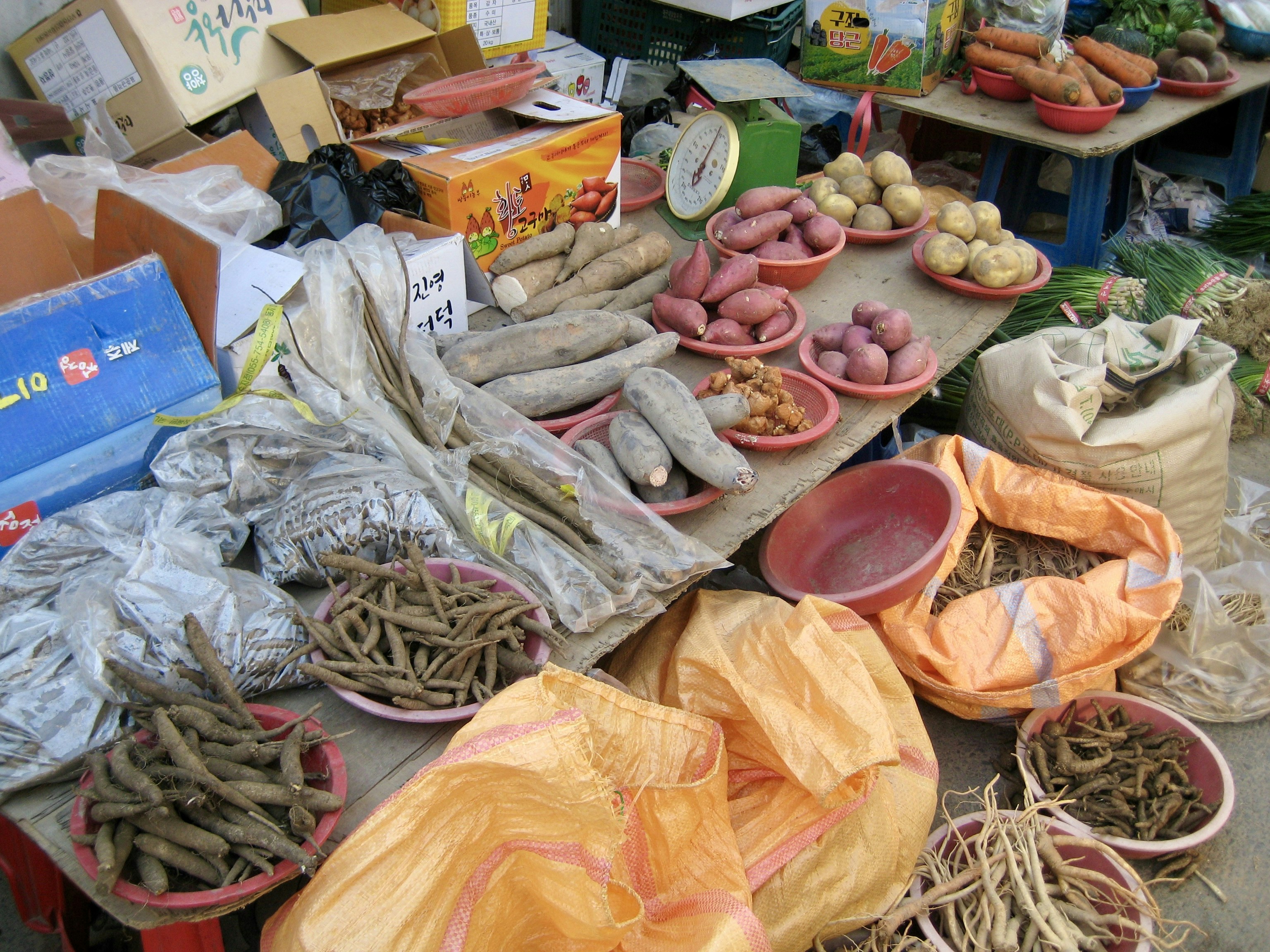 Various root vegetables and herbs displayed at a market.