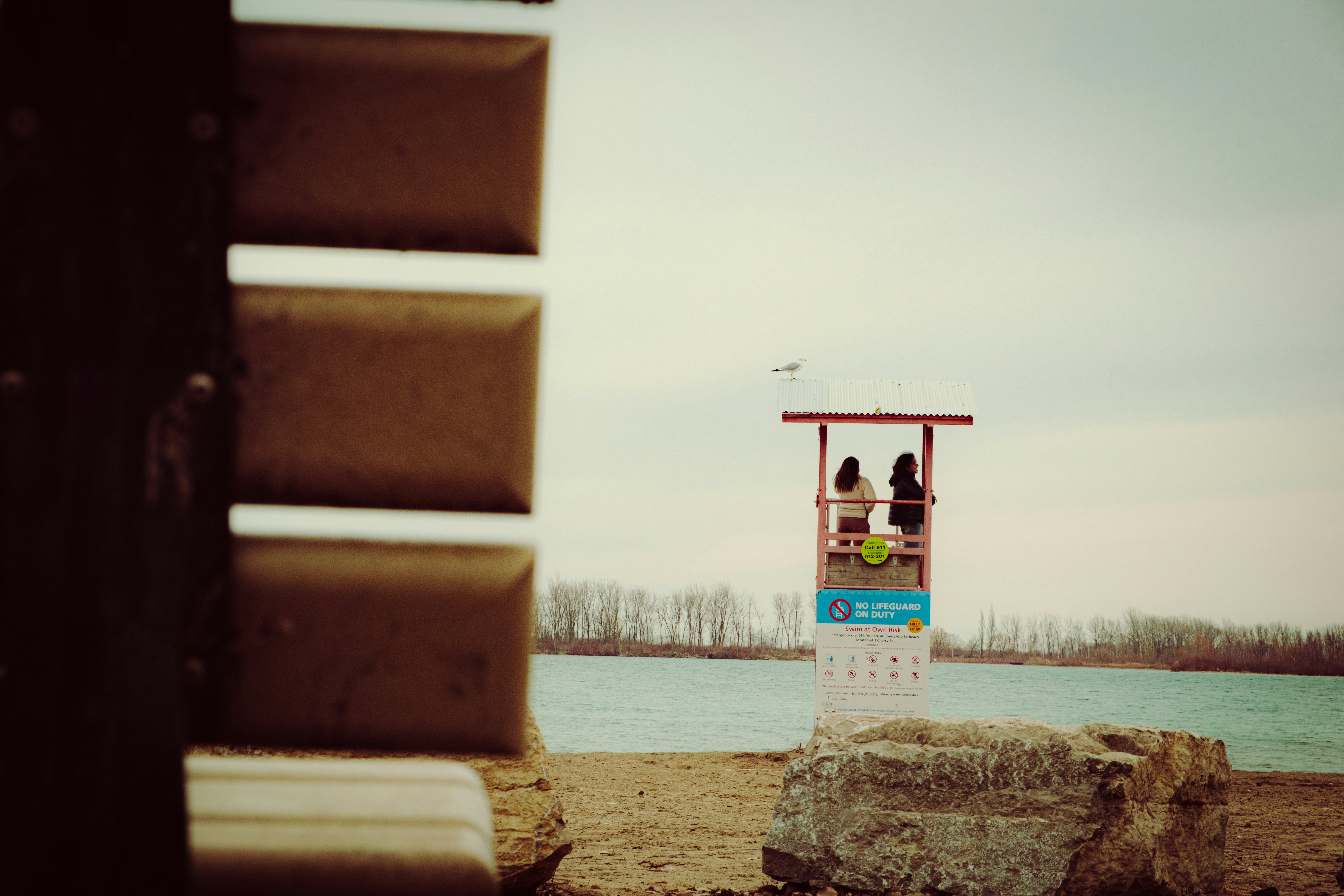 Dos personas están sentadas en una torre de socorrismo junto al agua.