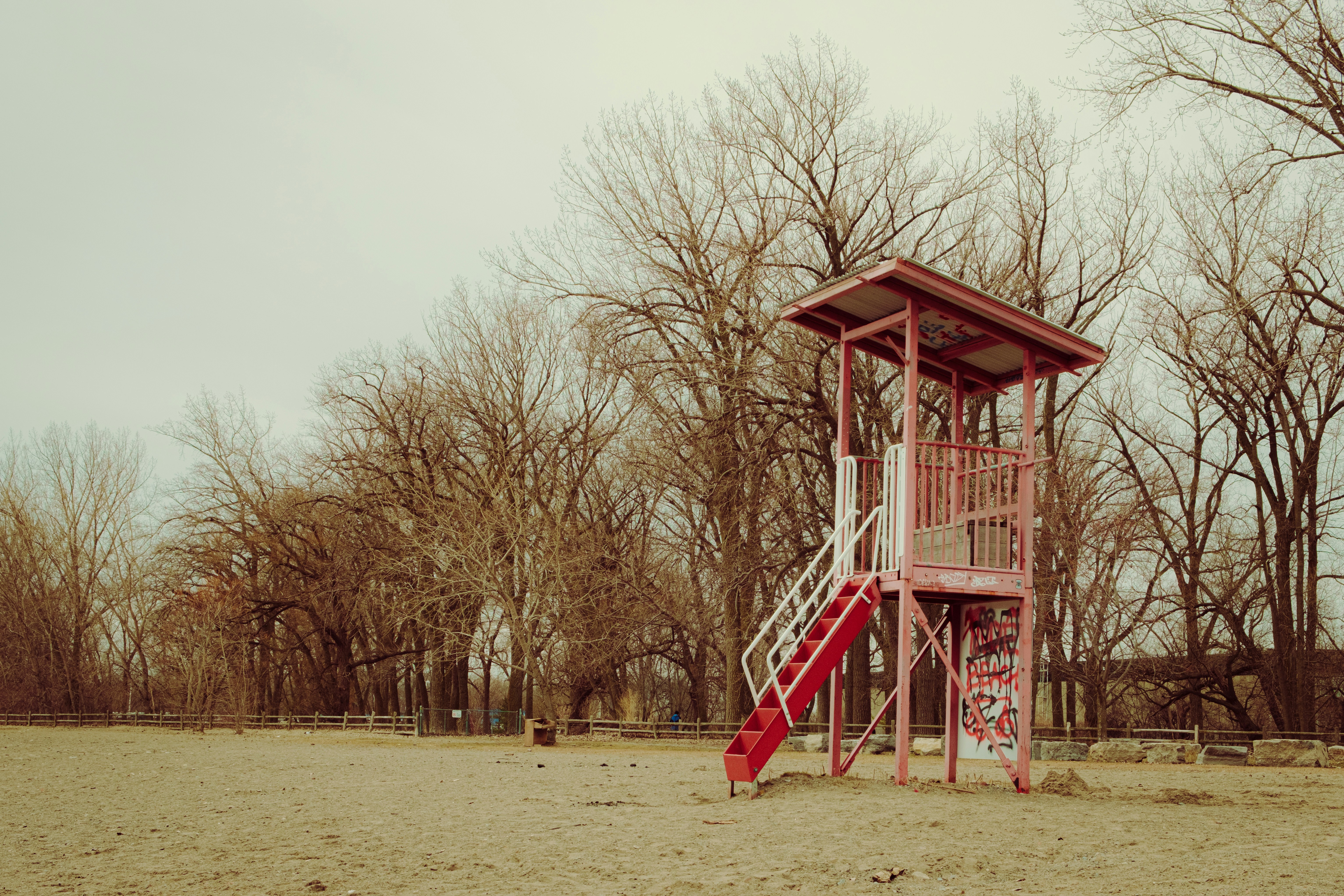 Una torre de socorrismo roja se alza en una playa de arena.