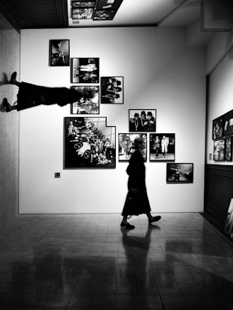 A person walks past framed art on a gallery wall