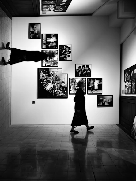A person walks past framed art on a gallery wall.