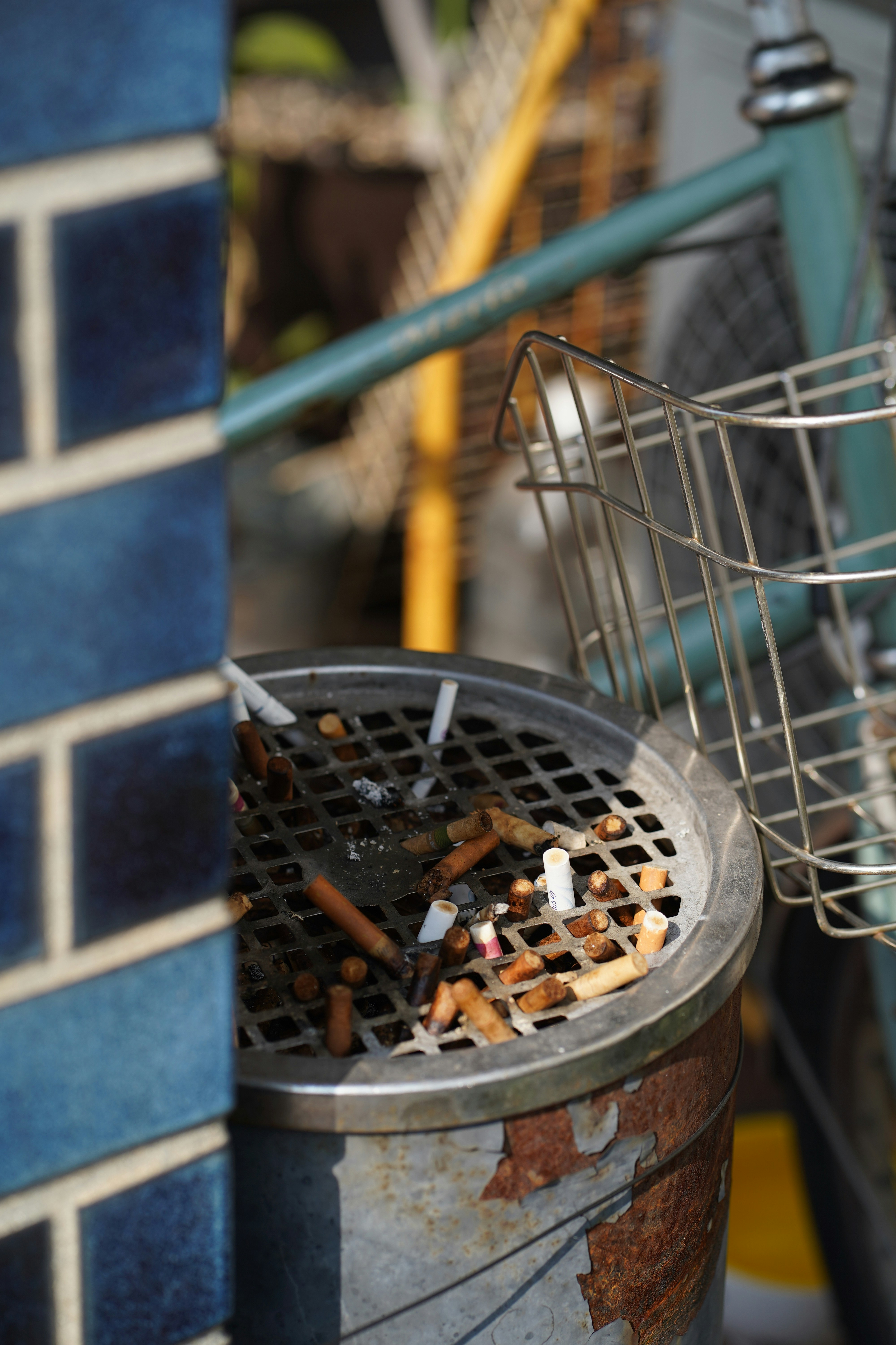 Cendrier rempli de mégots près de briques bleues