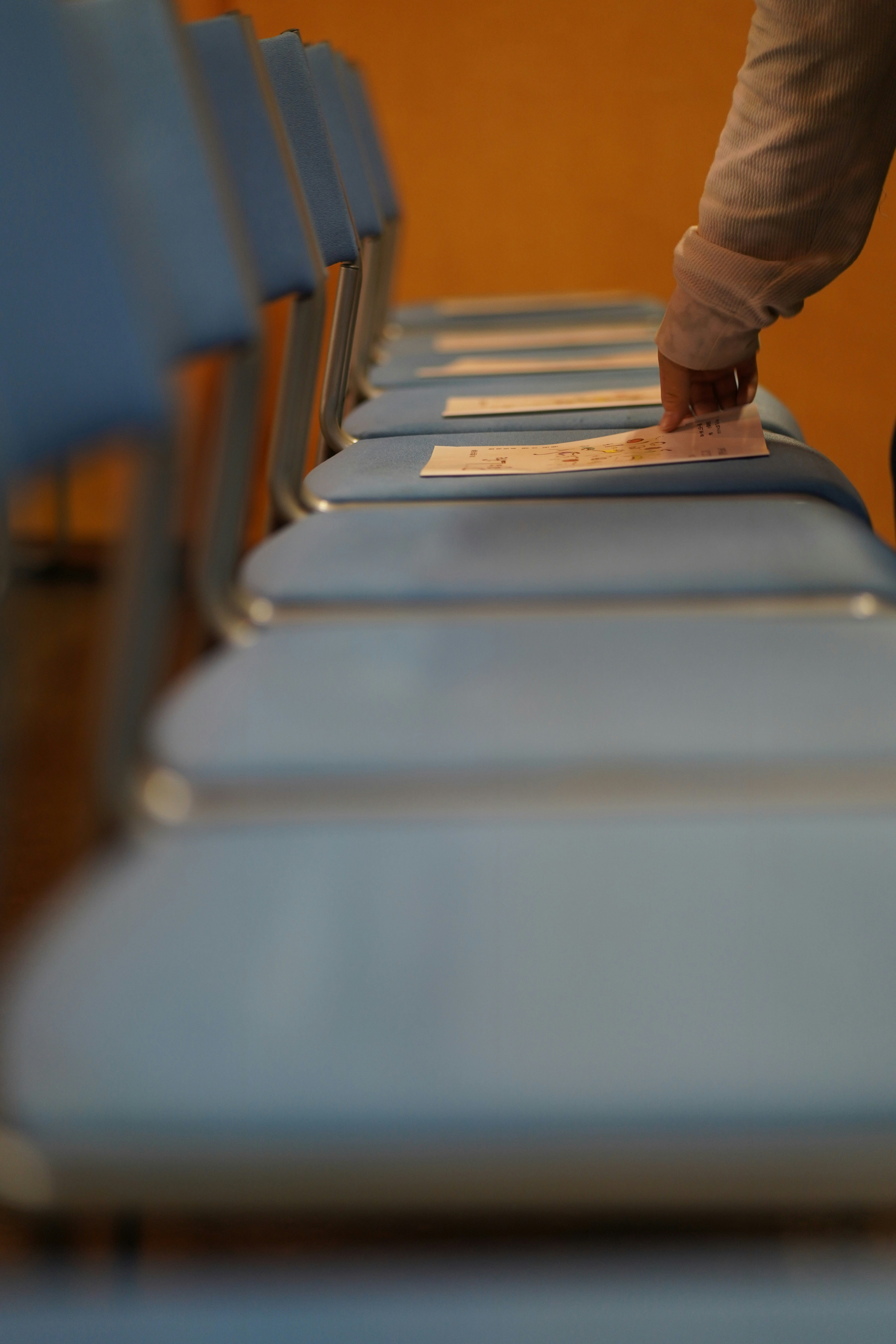 Une main tend la main vers un papier sur une chaise bleue.