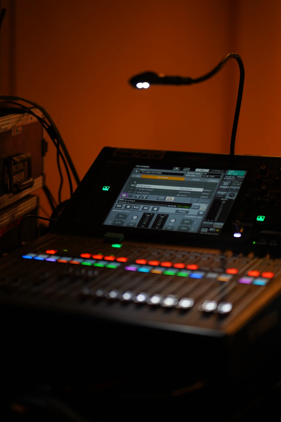 Close-up of a digital audio mixing console with colorful faders