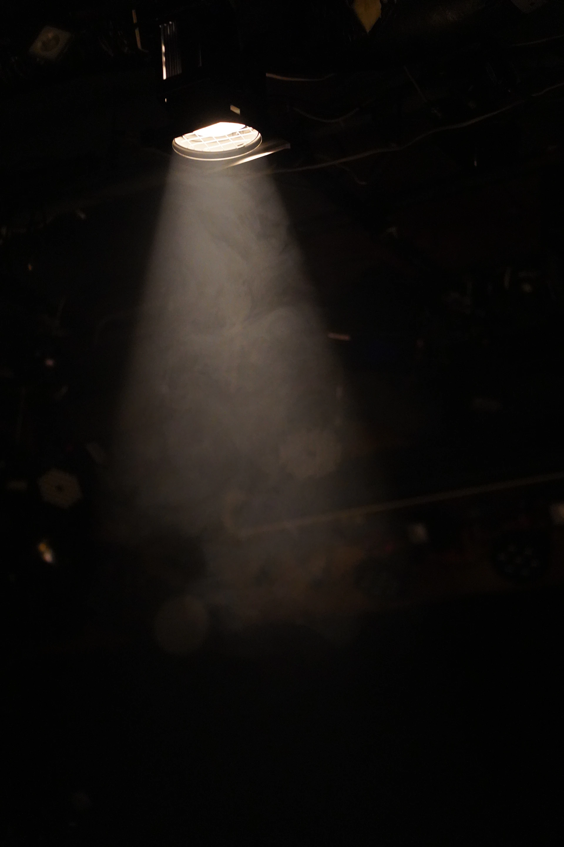 A single spotlight shines through smoke in a dark room.
