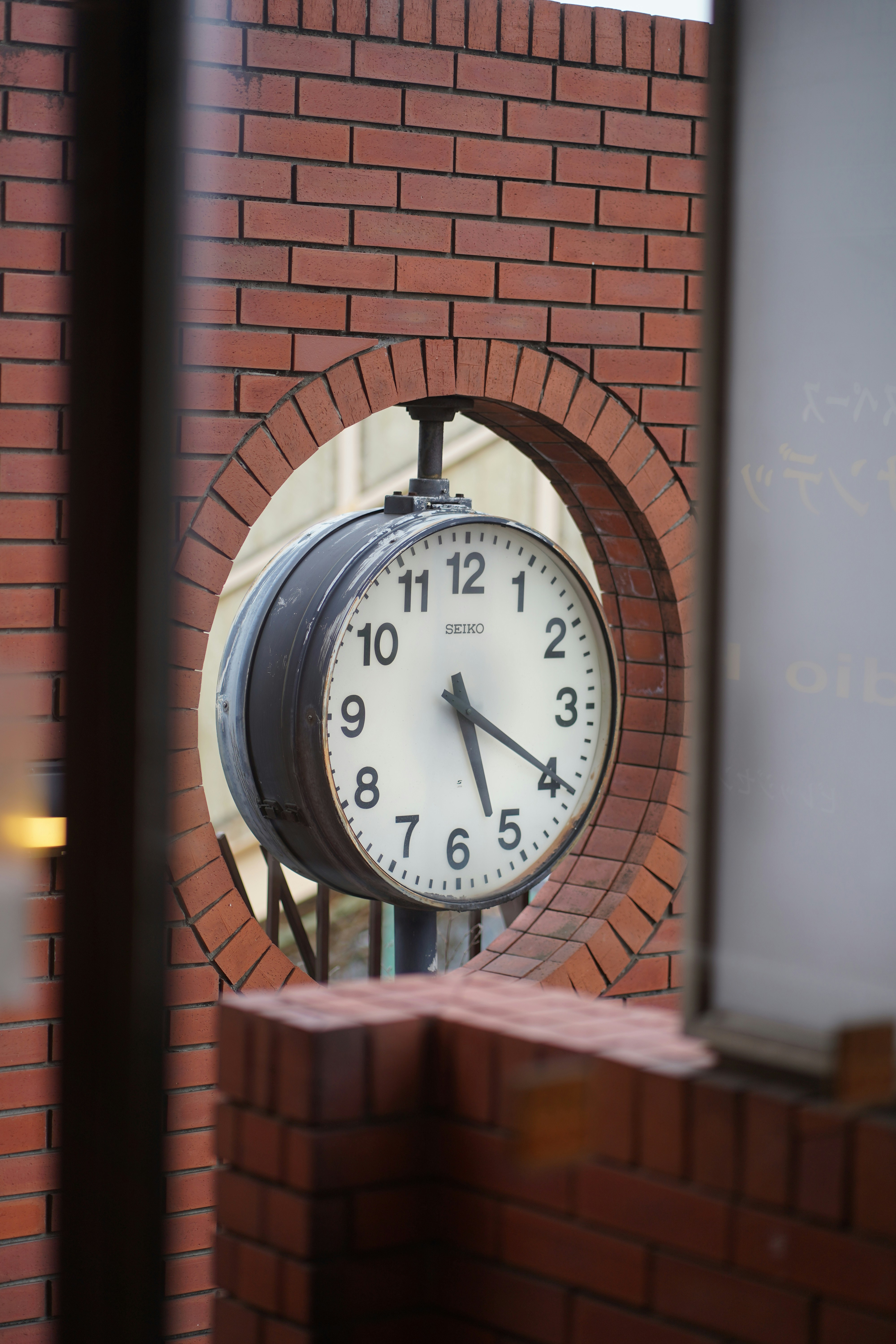 Une grande horloge ronde posée sur un mur de briques.