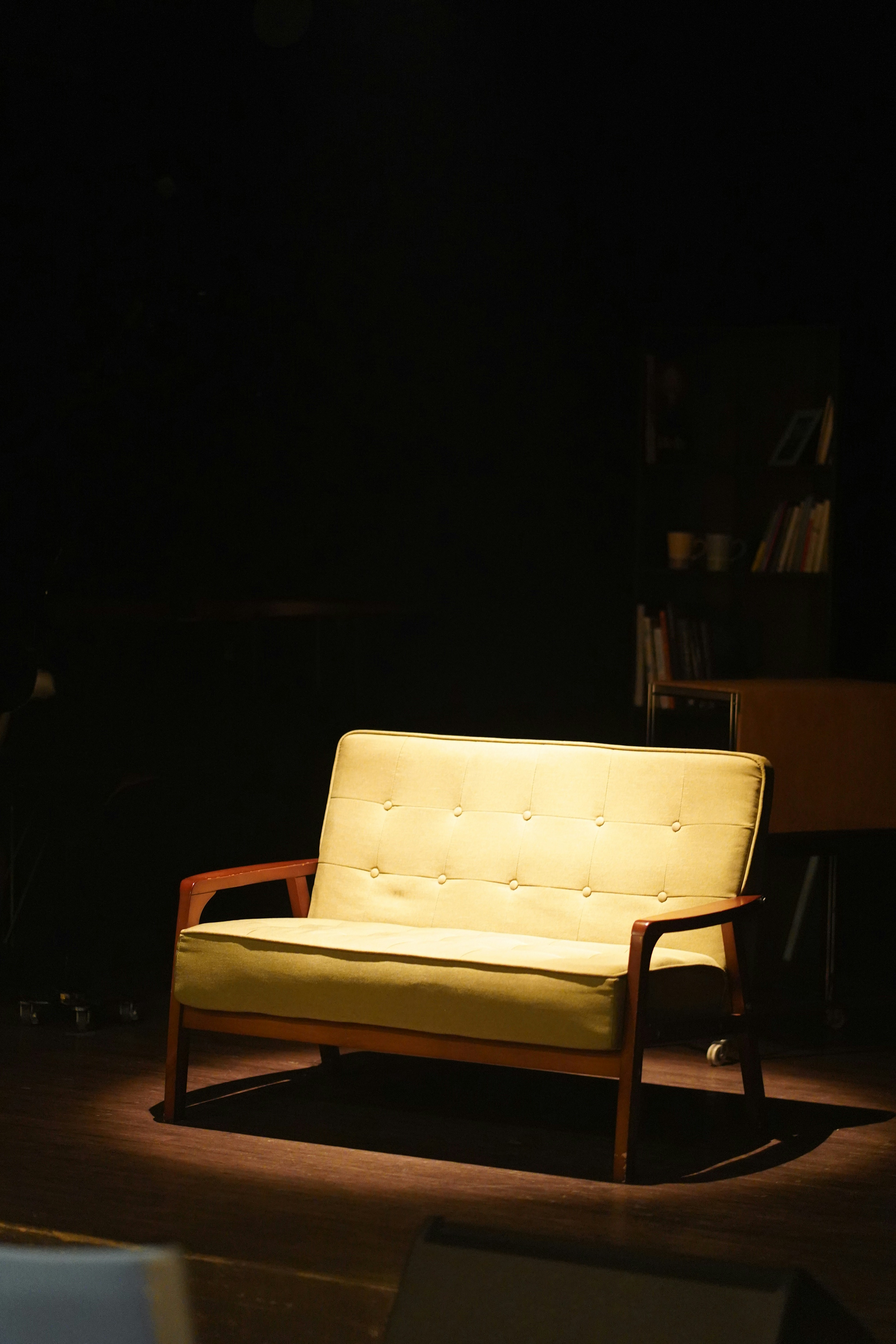 Ein Retro-Sofa, beleuchtet von einem Scheinwerfer auf einer Bühne.