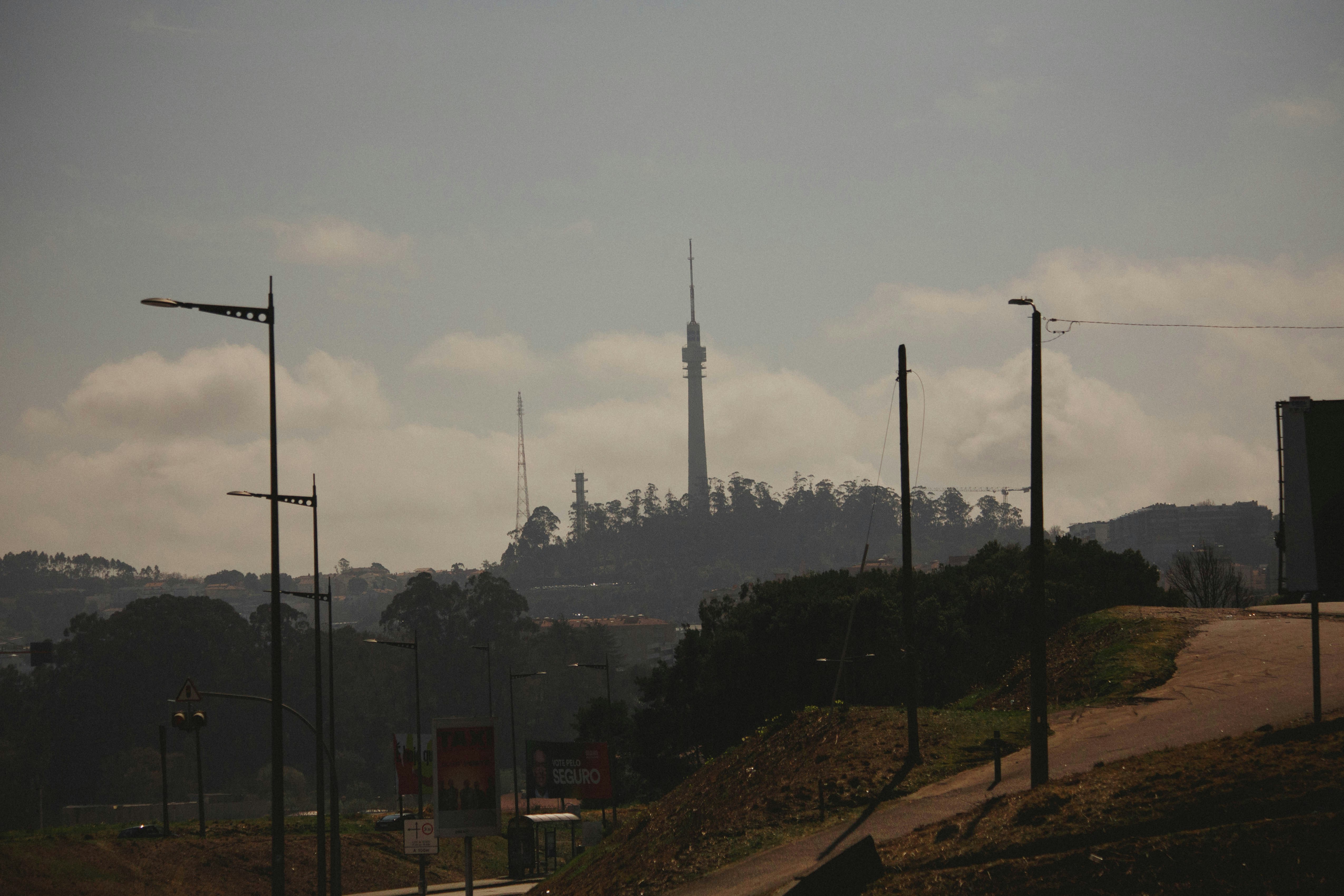 Distant tower on a hazy hilltop with trees and streetlights
