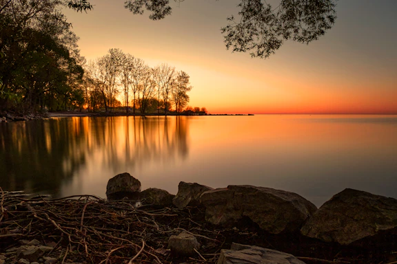 Sunset over a calm lake with trees reflected