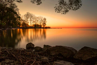 Sunset over a calm lake with trees reflected
