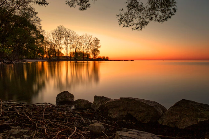 Sunset over a calm lake with trees reflected