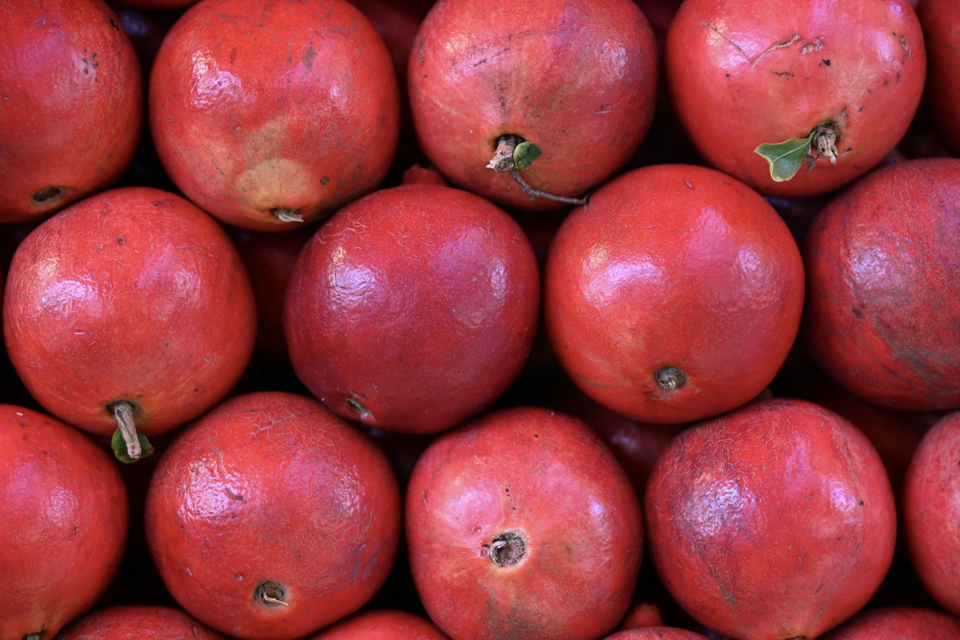A close-up view of ripe red pomegranates stacked together.